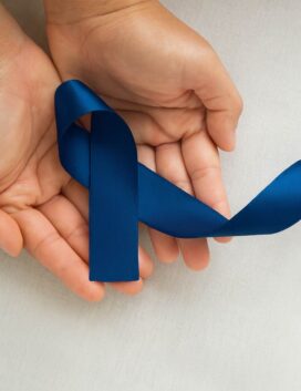 Hands holding a dark blue awareness ribbon for mesothelioma and asbestos-related disease awareness