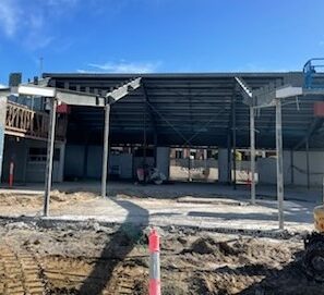 Partially demolished commercial building with exposed frame and construction machinery