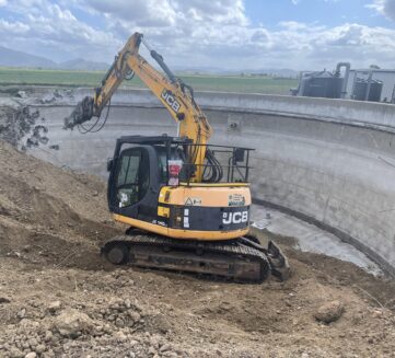 Excavator breaking reinforced tank wall during industrial demolition in Queensland
