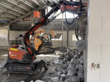 Excavator performing internal strip out and selective demolition inside a commercial building for Razor Asbestos.